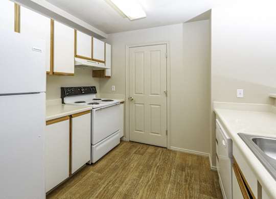 A kitchen with white appliances and wooden floors.at Sunset Ridge, West Jordan, UT