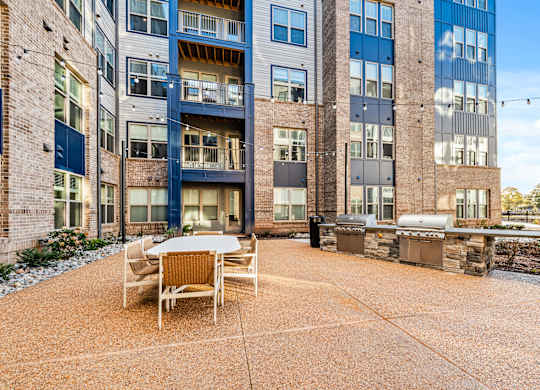 A patio area with a table and chairs in front of a multi-story building.