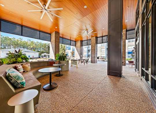 A modern outdoor seating area with a wooden ceiling and concrete flooring.
