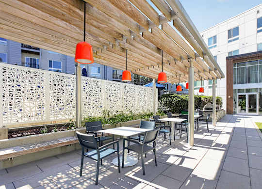 A patio with a table and chairs under a wooden canopy.