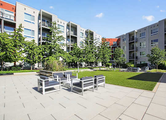 A sunny day at a modern apartment complex with a seating area in the foreground.