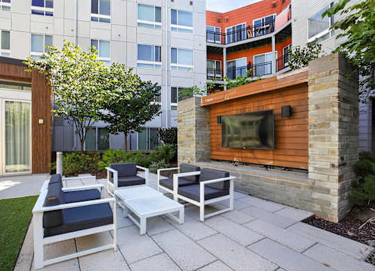 A modern outdoor seating area with a television on a wooden wall.