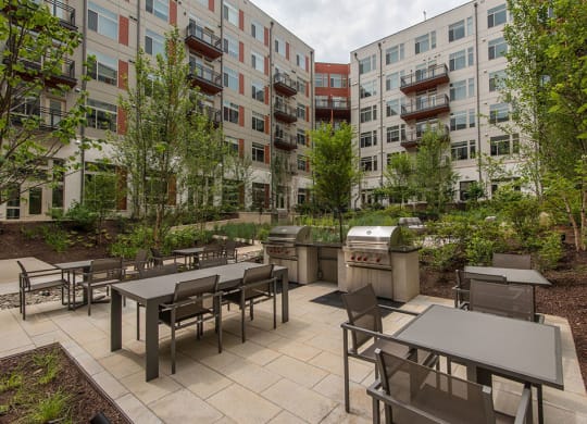 Outdoor patio with tables and chairs and a grill at Highgate at the Mile in McLean, VA