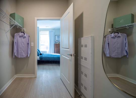A hallway with a bedroom at the end and two shirts hanging up at Jayde Parkside Apartments, Washington, DC