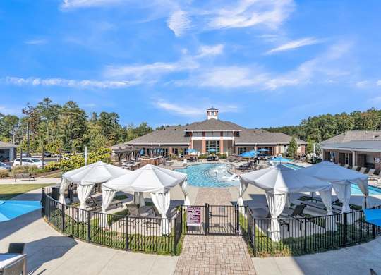 A large swimming pool surrounded by white umbrellas and lounge chairs.at The Aster Cary, Cary