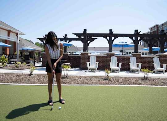 A woman is playing mini golf on a sunny day.at The Aster Cary, North Carolina, 27519