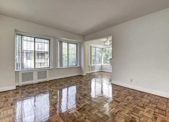 A room with a wooden floor and two windows.