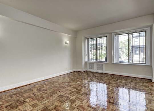 A room with a wooden floor and two windows.