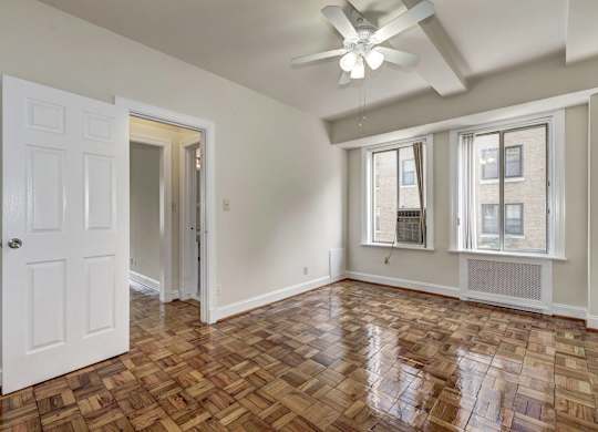 A room with a ceiling fan and wooden flooring.