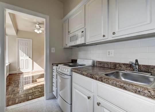 A kitchen with a white dishwasher and a granite countertop.