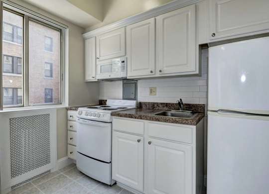 A kitchen with white appliances and cabinets.