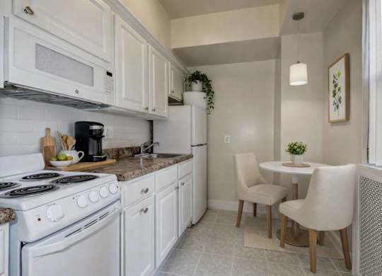 A kitchen with white appliances and a small table with two chairs.