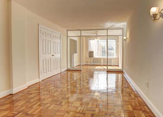 A long hallway with a wooden floor and a white door.