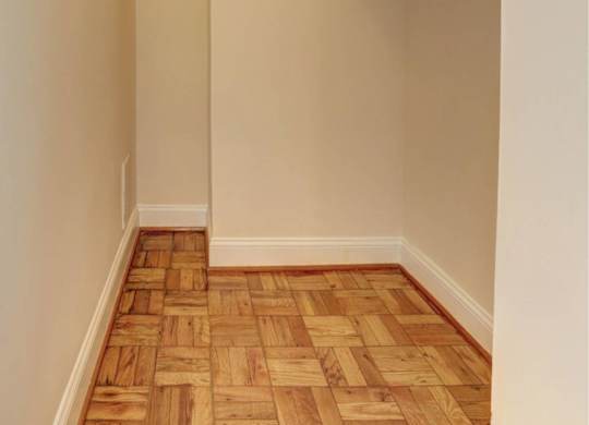A hallway with a wooden floor and white walls.