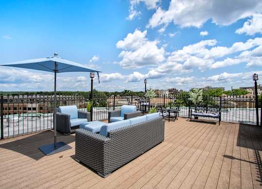 A patio with a white umbrella and a black fence.