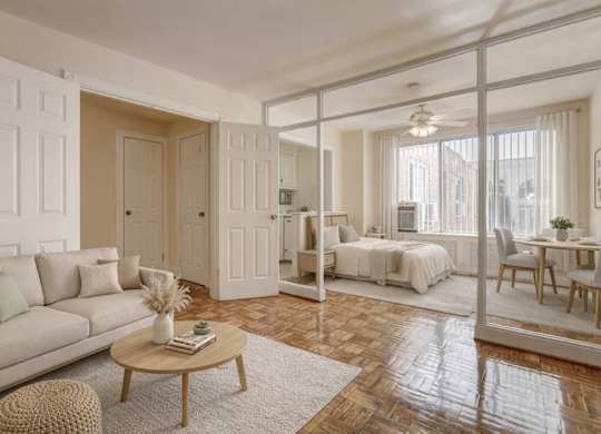 A living room with a couch, a coffee table, and a bed in the background.