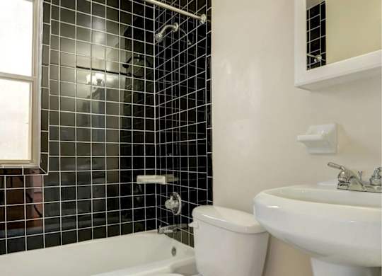 A white toilet sits in a bathroom with black tiles.