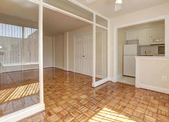 A room with a wooden floor and a kitchen in the background.