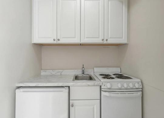 A white kitchen with a dishwasher, sink, and stove.
