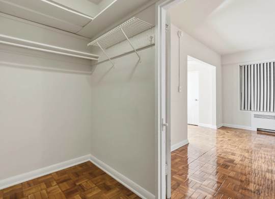 A room with white walls and wooden flooring with a doorway leading to another room.