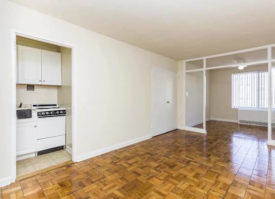 A kitchen with a stove top oven and a wooden floor.