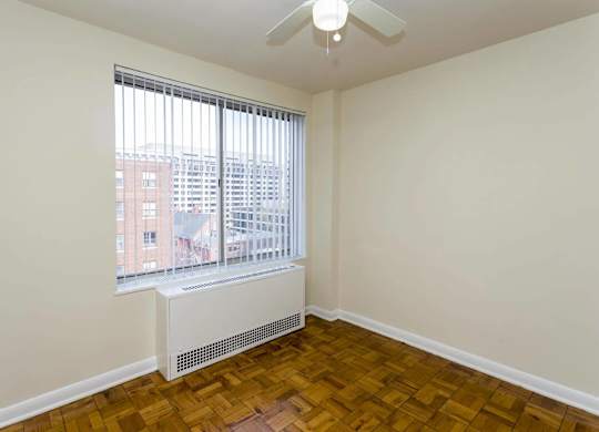 A room with a window and a fan on the ceiling.