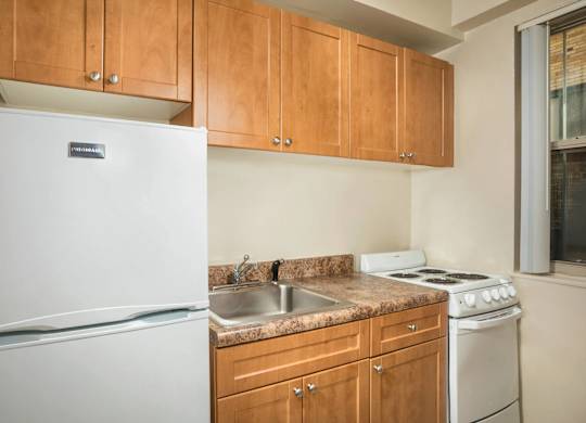 A kitchen with a white fridge, wooden cabinets, and a white stove.