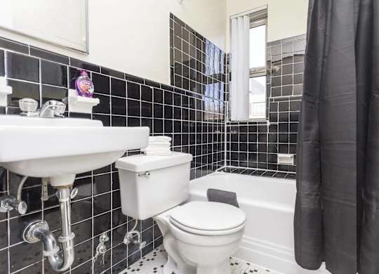 A white toilet and sink in a black and white tiled bathroom.
