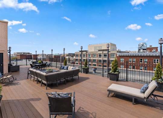 A wooden deck with a table and chairs is surrounded by a black fence.