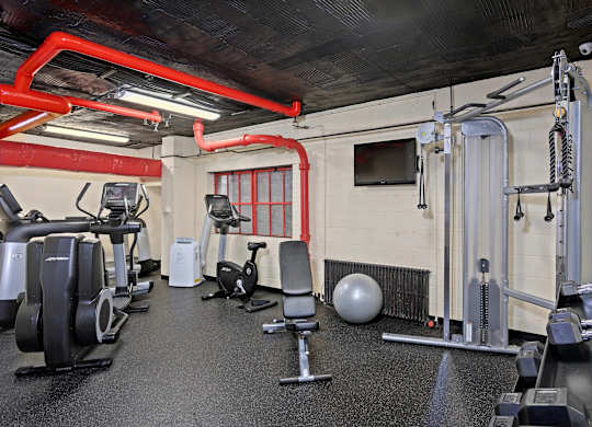 A gym with a variety of equipment including weights and cardio machines.