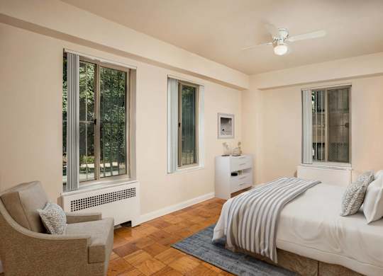 A bedroom with a bed, chair, and window.