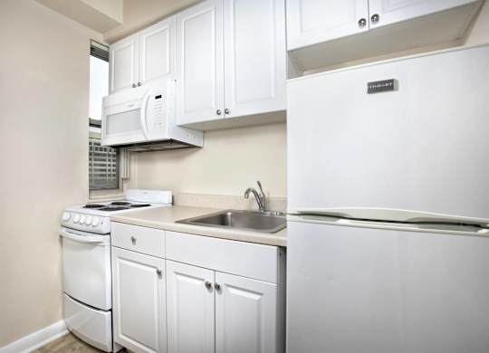 A white kitchen with a refrigerator, stove, and microwave.