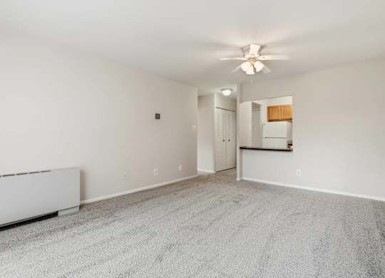 A spacious room with a carpeted floor and a ceiling fan.