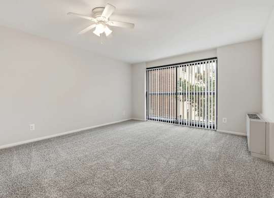 A room with a ceiling fan and a window with blinds.
