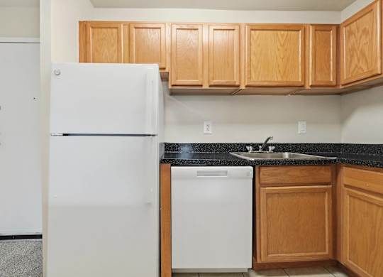 A white refrigerator is in a kitchen with wooden cabinets.