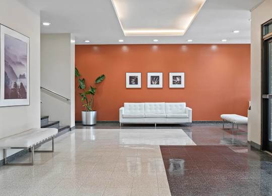 A white sofa sits in front of an orange wall in a modern room.