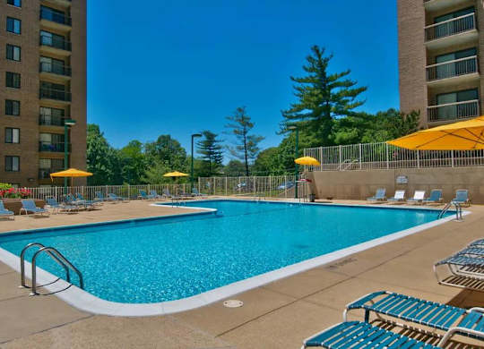 A large swimming pool surrounded by lounge chairs and umbrellas.