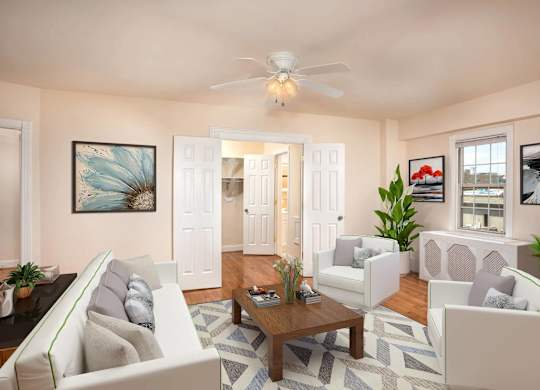 A living room with a white couch, a coffee table, and a ceiling fan.