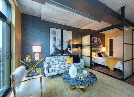 A modern living room with a grey couch and a yellow throw pillow.