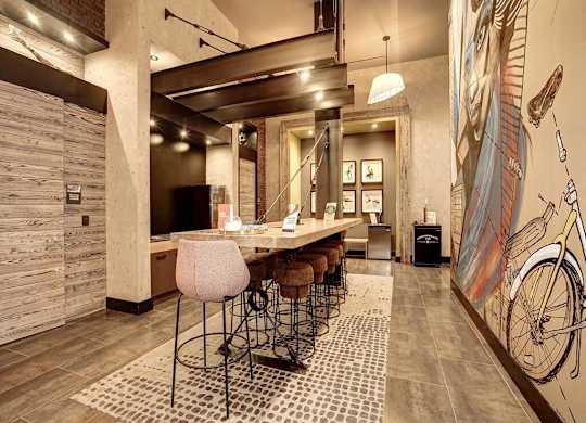 A modern kitchen with a bar area and a mural of a bicycle on the wall.