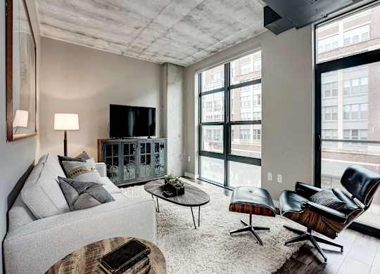 A living room with a grey couch, a wooden coffee table, and a black leather chair.