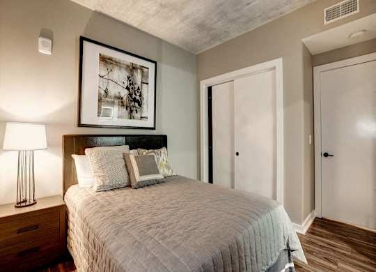 A bedroom with a bed, nightstand, and lamp.