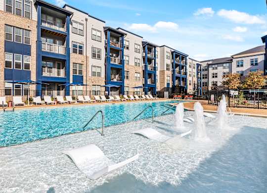 A pool with a fountain and lounge chairs at Preston Ridge Cary, NC.