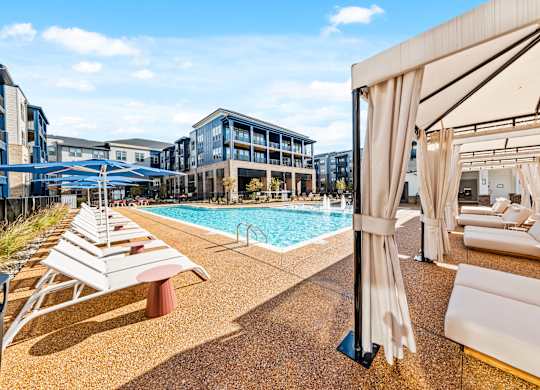 A pool area with sun loungers and a cabanas at Preston Ridge Apartments in Cary, NC.