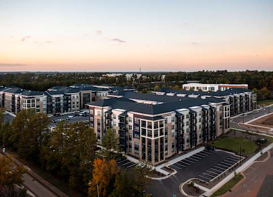 A large, modern building complex with a parking lot in front.