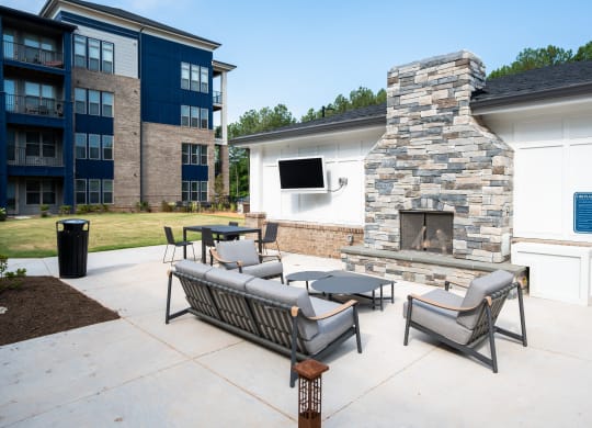 an outdoor patio with furniture and a stone fireplace at Preston Ridge, Cary, 27513