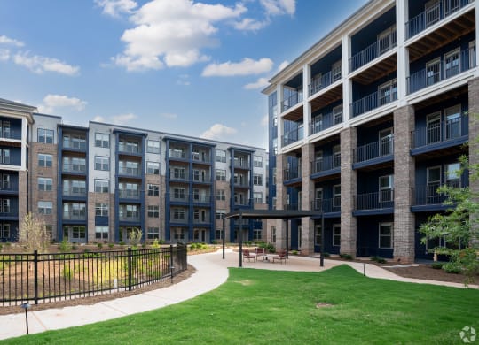 an exterior view of an apartment building with green grass and a walkway at Preston Ridge Cary, NC