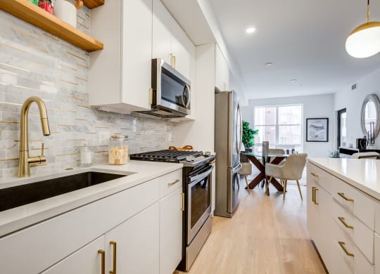 a kitchen with white cabinets and stainless steel appliances and a sink at Rialto, District of Columbia
