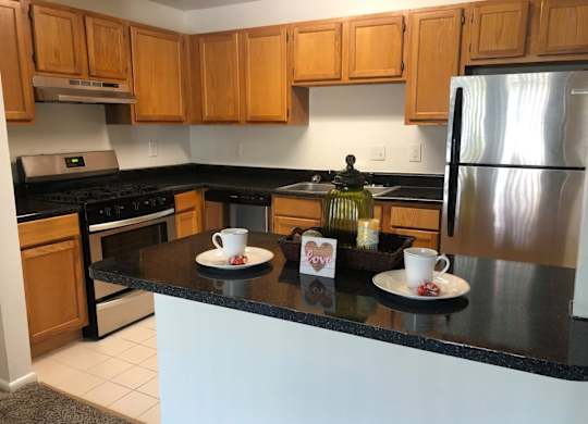 A kitchen with wooden cabinets and a black countertop at Shenandoah Station Apartments, Virginia