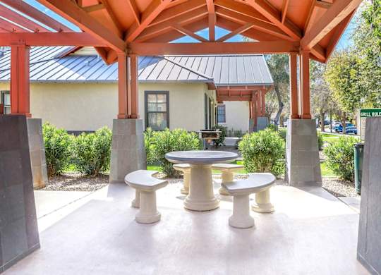A pavilion with a table and chairs is surrounded by concrete pillars at Roosevelt Commons Apartments, Arizona, 85003